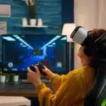 A woman playing VR gaming with VR headset and Joystick, siting on the chair and enjoying the latest advancements in gaming technology.