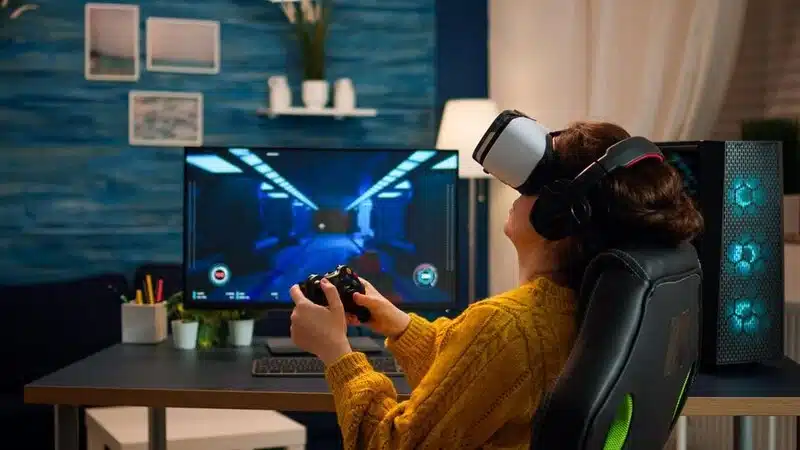 A woman playing VR gaming with VR headset and Joystick, siting on the chair and enjoying the latest advancements in gaming technology.